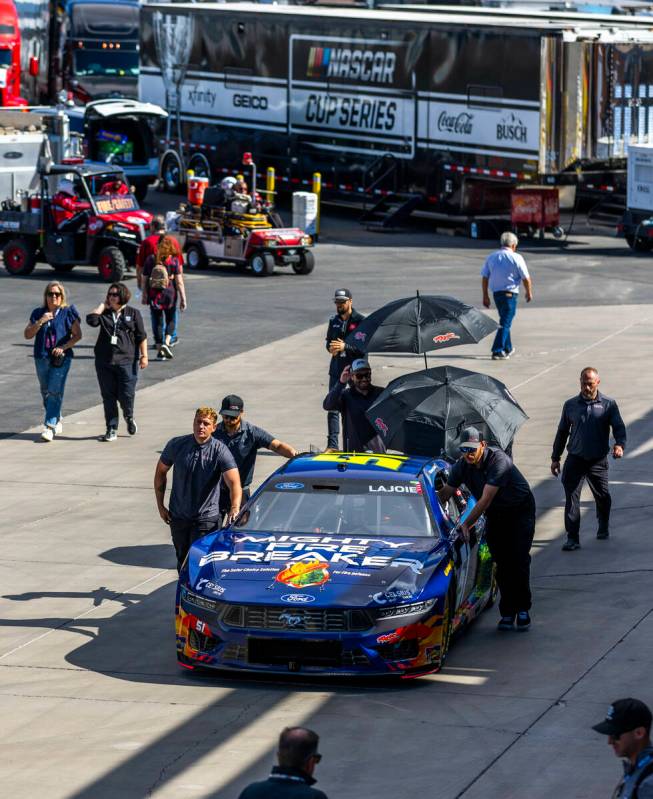 Crew members wheel Corey LaJoie's car past the Neon Garage before NASCAR Cup Series practice an ...