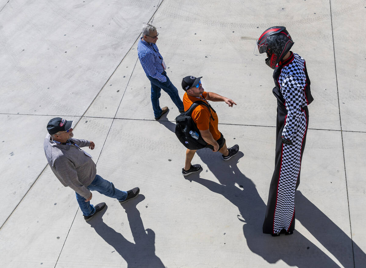 A fan looks up to a racing character with stilts about the Neon garage before NASCAR Cup Series ...