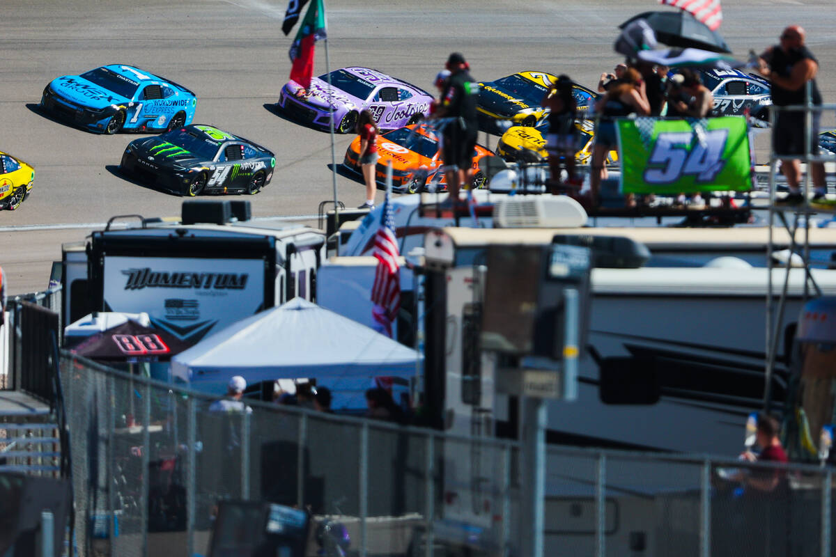 Race fans cheer on NASCAR drivers as they zoom by during the South Point 400 NASCAR Cup Series ...