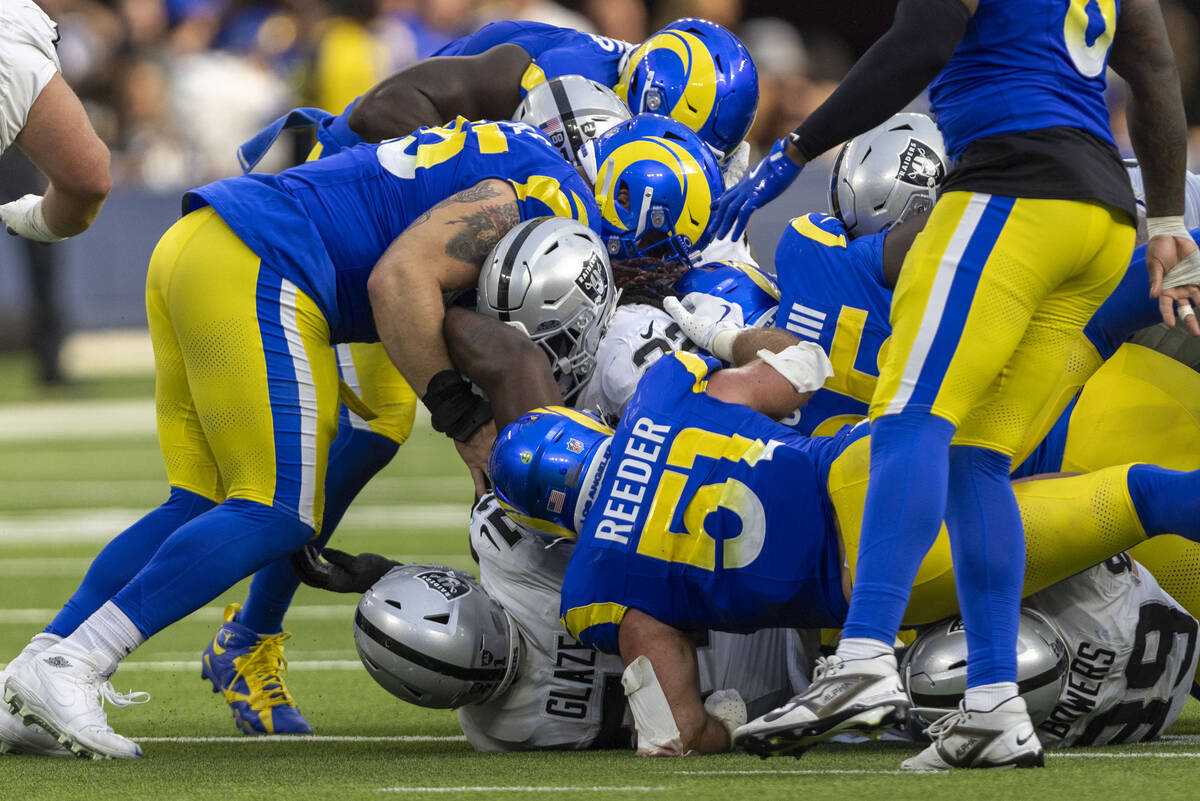 Raiders running back Alexander Mattison (22) squeezes past several Los Angeles Rams defenders i ...