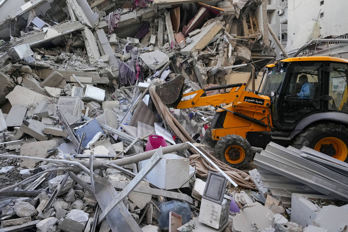 Rescue workers use a bulldozer to remove rubble of destroyed buildings at the site of an Israel ...