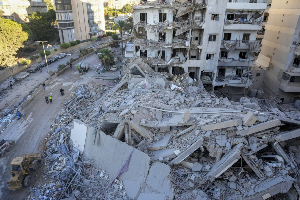 Rescue workers use a bulldozer to remove rubble of destroyed buildings at the site of an Israel ...