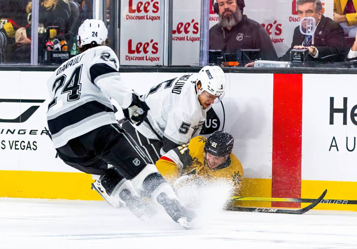 Golden Knights center Brett Howden (21) still fights for the puck while down on the ice with Lo ...