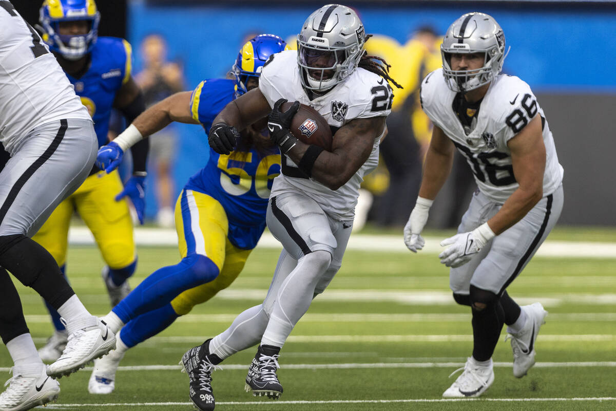 Raiders running back Alexander Mattison (22) rushes past Los Angeles Rams linebacker Christian ...