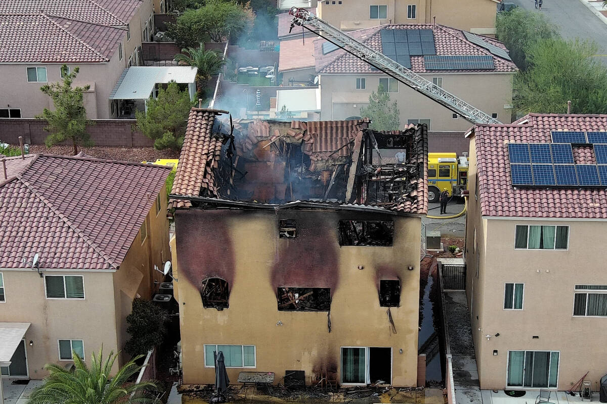 The remains of a charred house are seen after an early morning fire at 8332 Langhorne Creek Str ...