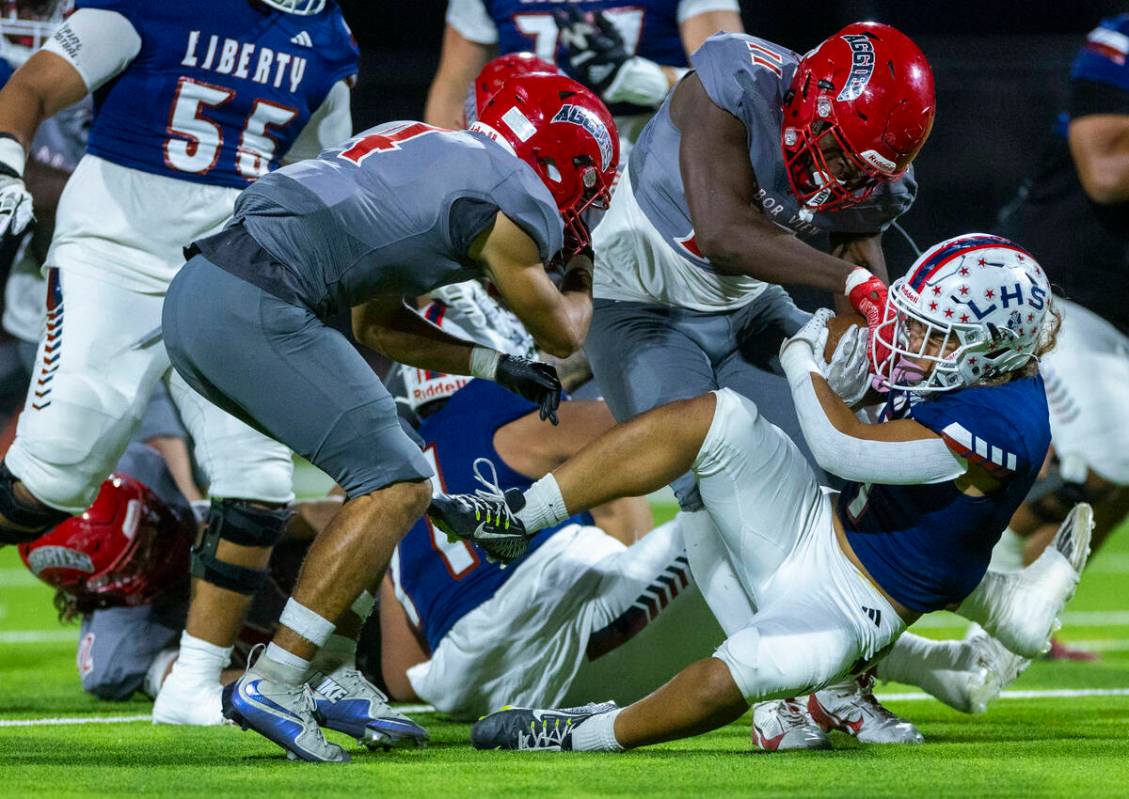 Liberty running back Ezra Sanelivi (1) hangs on to the ball after a run as Arbor View defensive ...