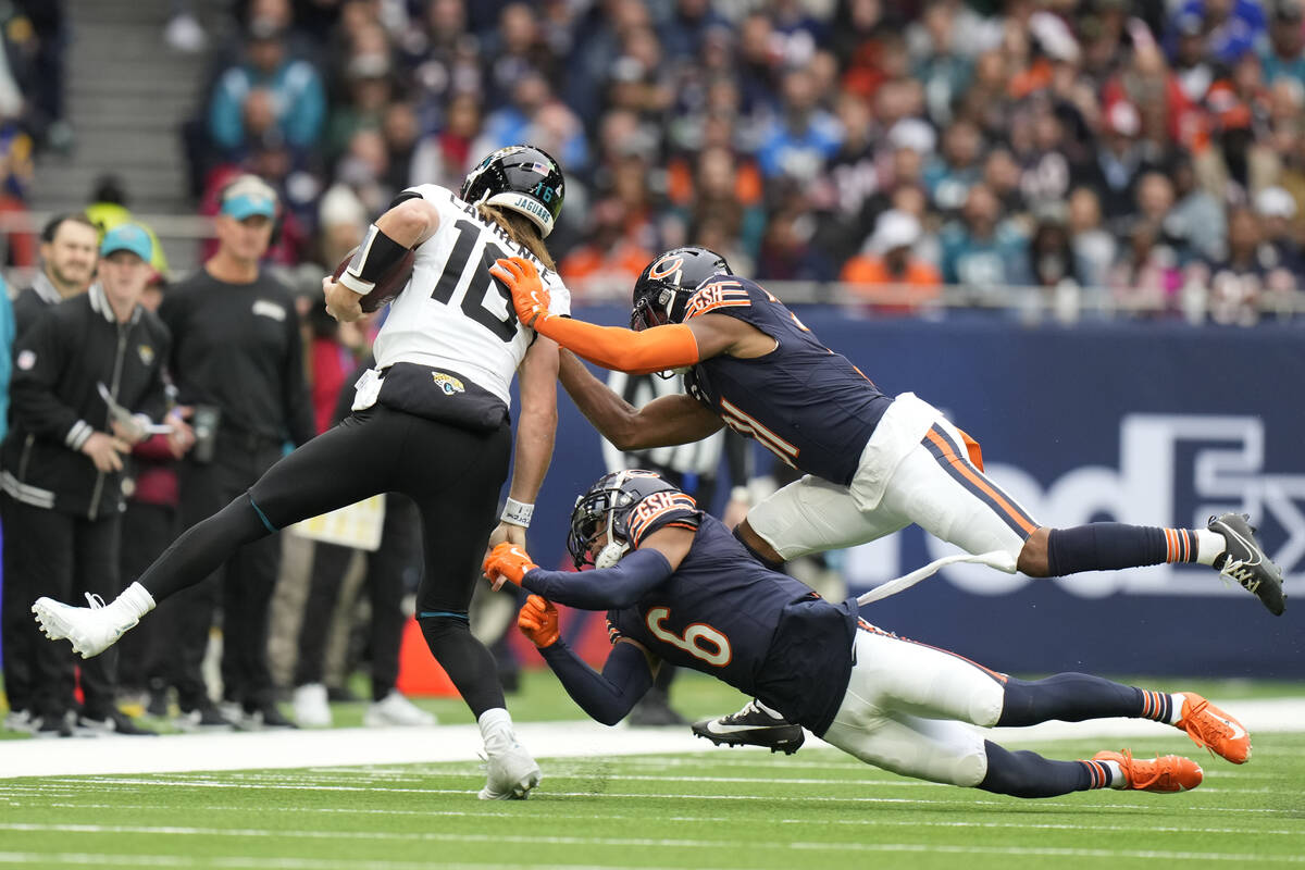 Jacksonville Jaguars quarterback Trevor Lawrence (16) is tackled by Chicago Bears safety Kevin ...