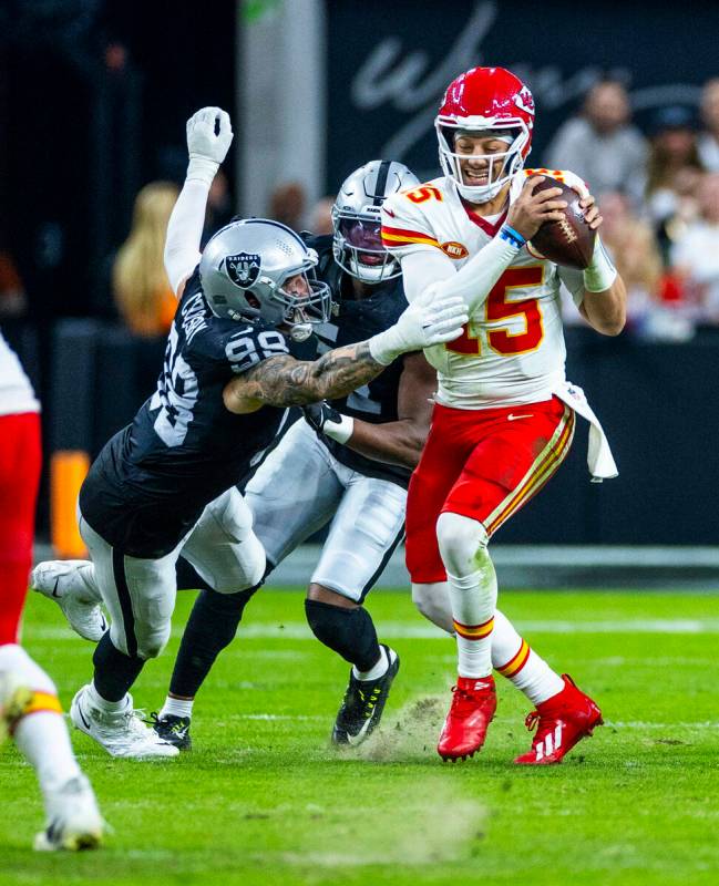 Raiders defensive end Maxx Crosby (98) grabs Kansas City Chiefs quarterback Patrick Mahomes (15 ...