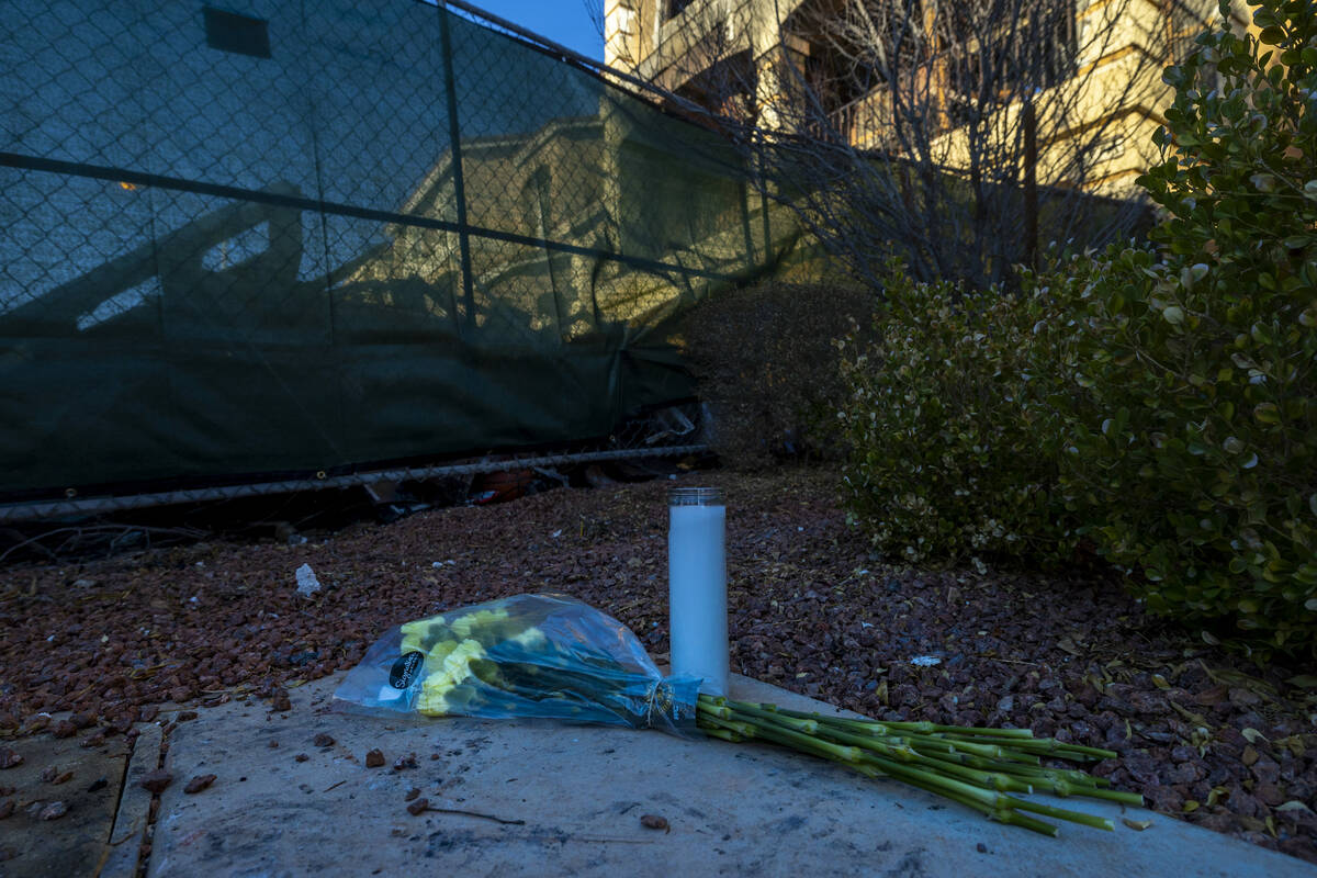 Flowers and a candle left near emergency fencing about the exterior of fatal house fire at 8332 ...