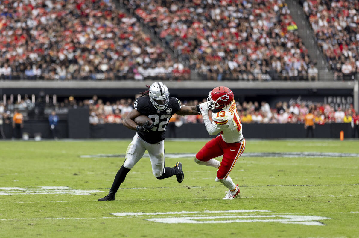 Raiders running back Alexander Mattison (22) pushes Kansas City Chiefs safety Nazeeh Johnson (1 ...