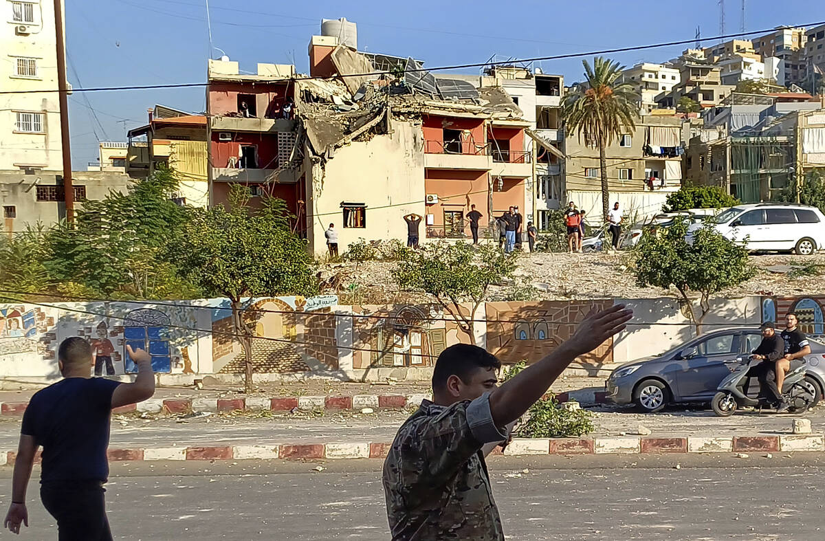 A Lebanese soldier asks journalists to move away from the scene near a building hit in an Israe ...