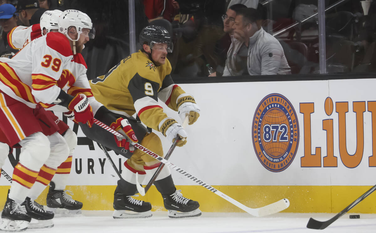 Golden Knights center Jack Eichel (9) skates with the puck under pressure from Calgary Flames r ...