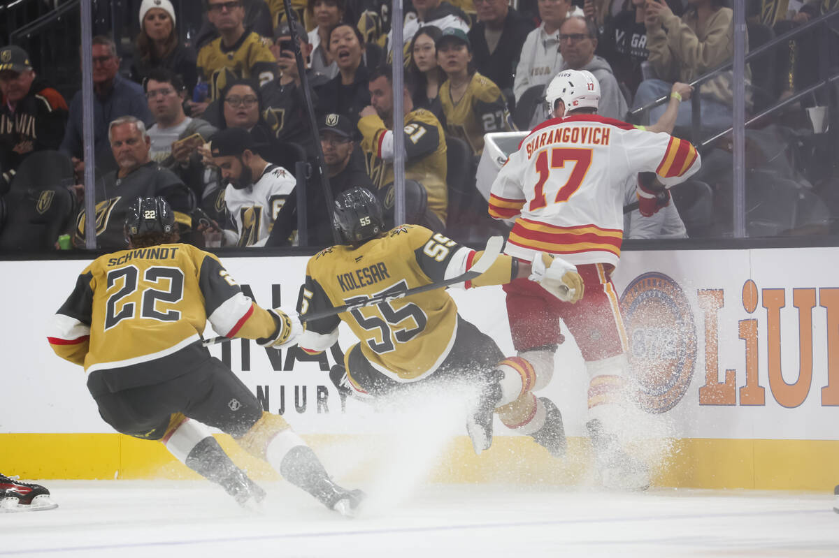 Golden Knights right wing Keegan Kolesar (55) gets tripped up between Calgary Flames center Yeg ...