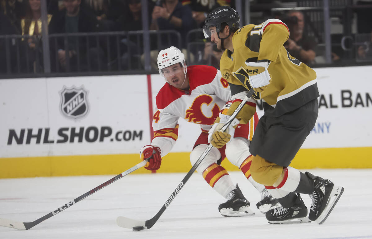 Golden Knights center Nicolas Roy (10) skates with the puck under pressure from Calgary Flames ...