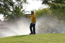 A landscaper talks on his cellphone as water sprinklers spray water at St. Rose Dominican Hospi ...