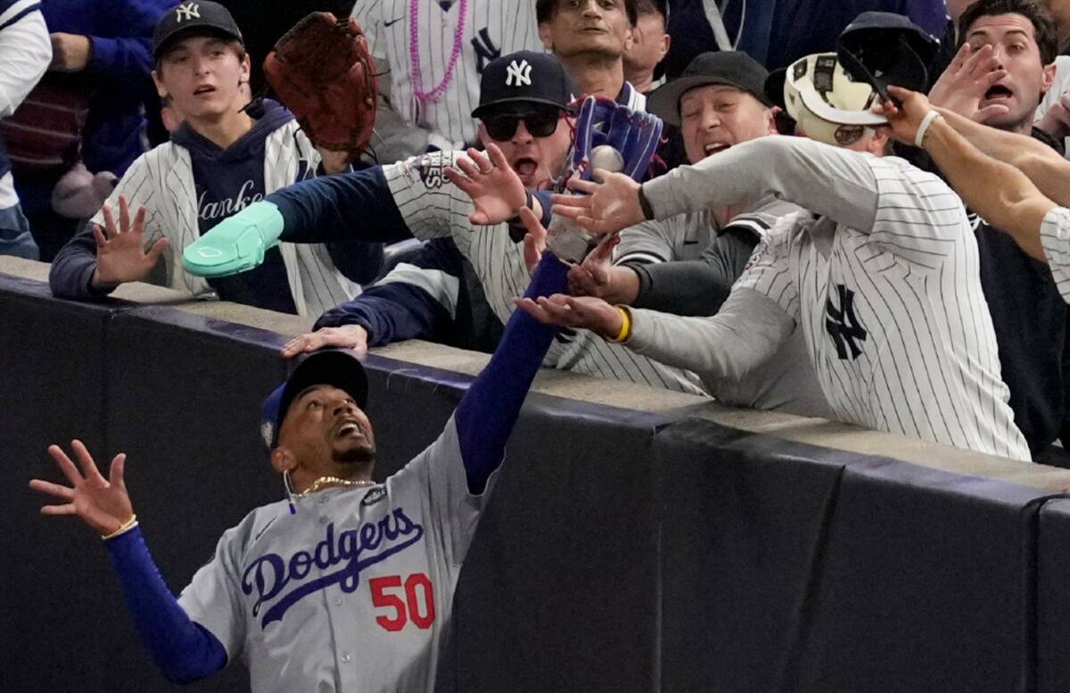 Fans interfere with a foul ball caught by Los Angeles Dodgers right fielder Mookie Betts during ...