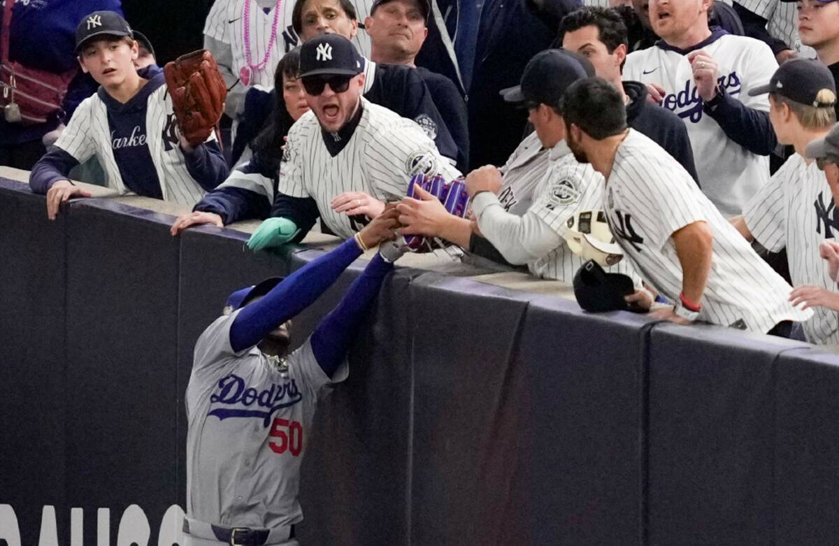 Fans interfere with a foul ball caught by Los Angeles Dodgers right fielder Mookie Betts during ...