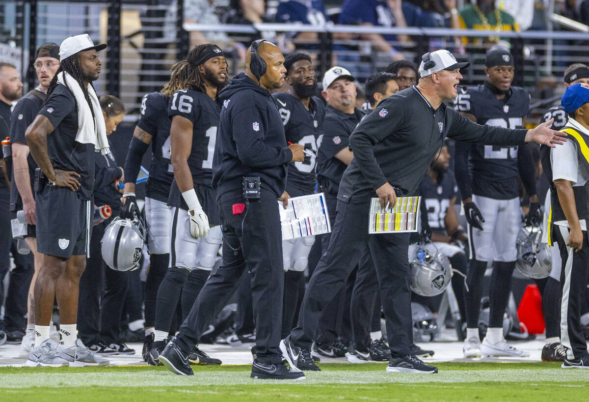 Raiders head coach Antonio Pierce looks on as offensive coordinator Luke Getsy argue flag from ...