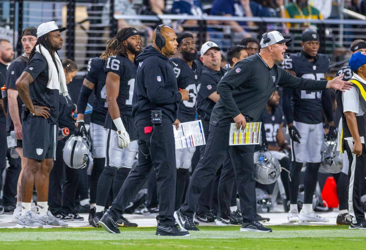 Raiders head coach Antonio Pierce looks on as offensive coordinator Luke Getsy argue flag from ...