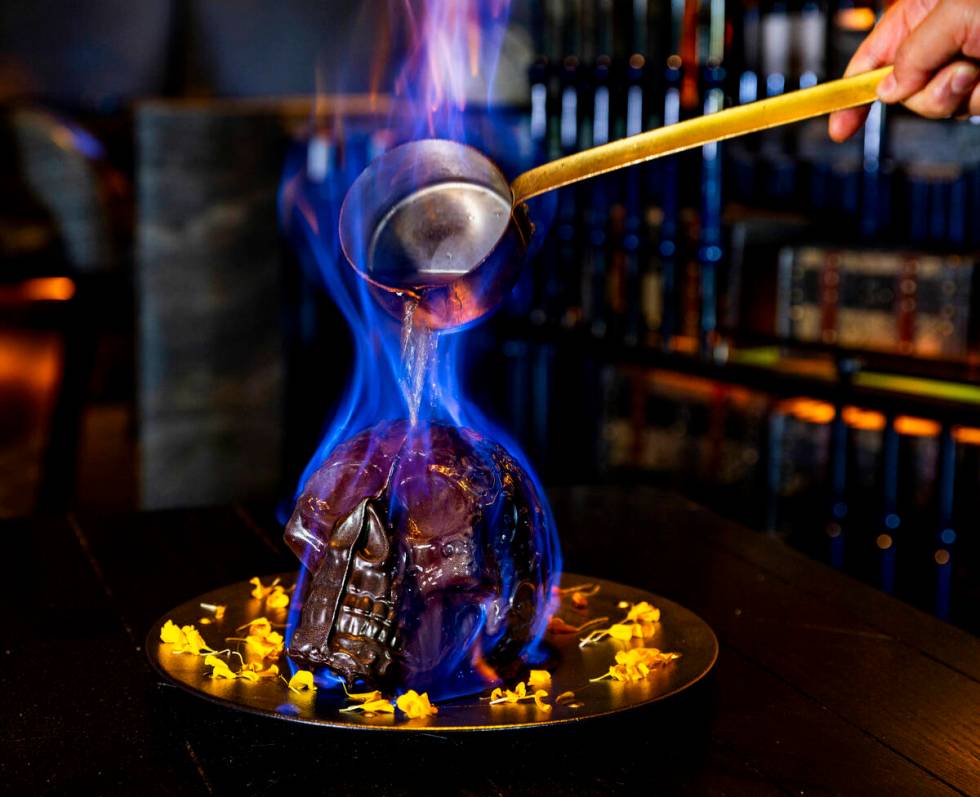 Hot chocolate mocha sauce is poured atop a Diablo Skull en Fuego dessert to reveal flan inside ...