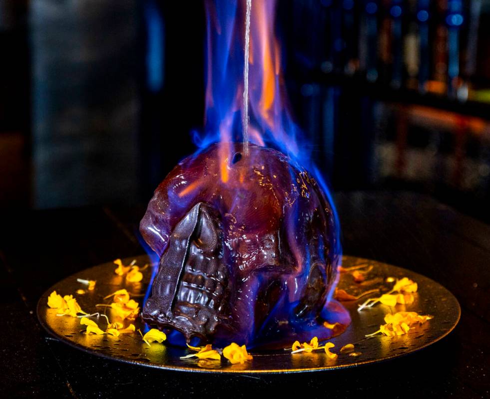 Hot chocolate mocha sauce is poured atop a Diablo Skull en Fuego dessert to reveal flan inside ...