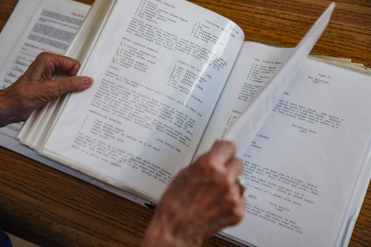 Evie Schild Hart looks through the cookbook documenting the recipes of her Christmas cookie clu ...