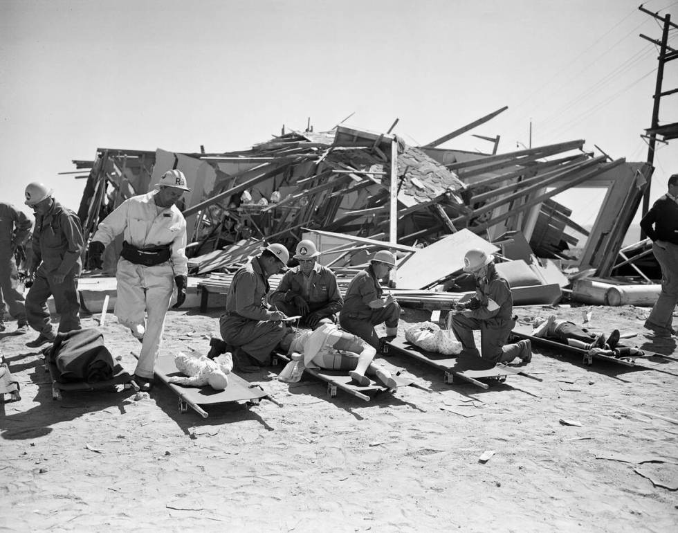 Civil defense workers place mannikins, which were exposed to yesterday's atomic blast, on stret ...