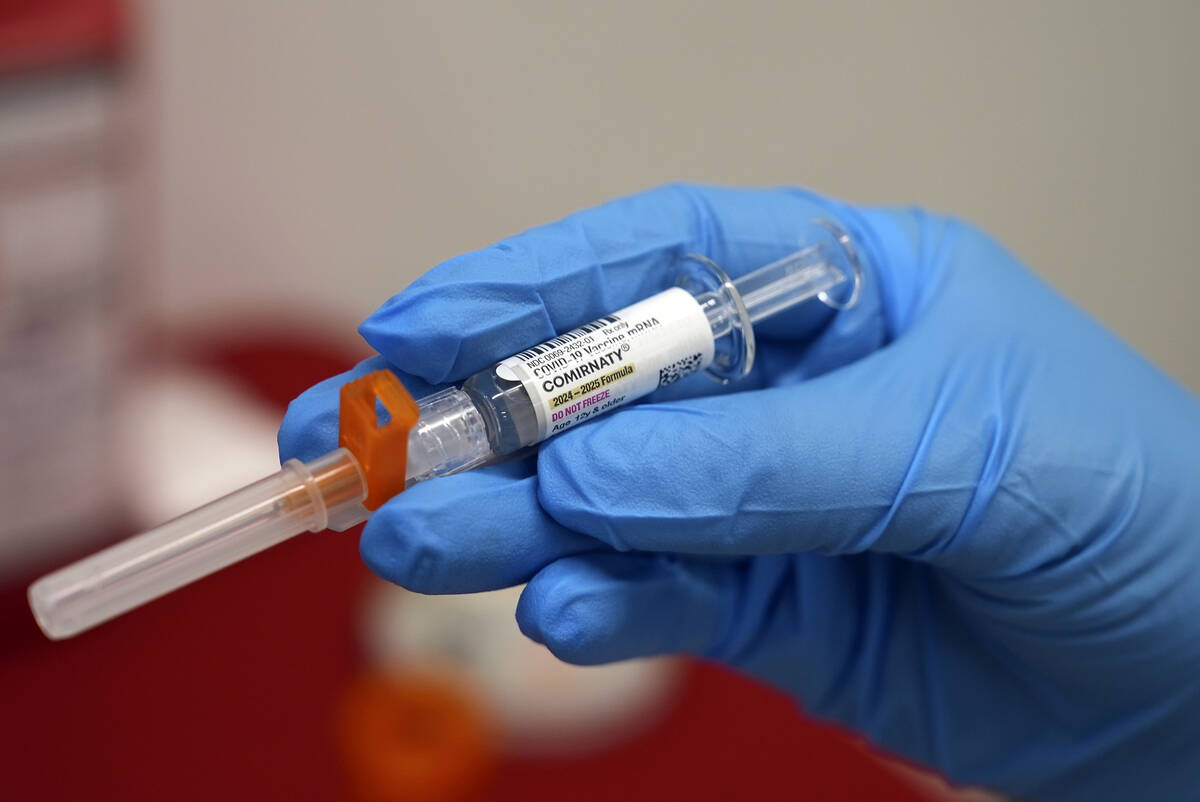 A pharmacist holds a COVID-19 vaccine at a pharmacy in New York, on Tuesday, Sept. 24, 2024. (A ...