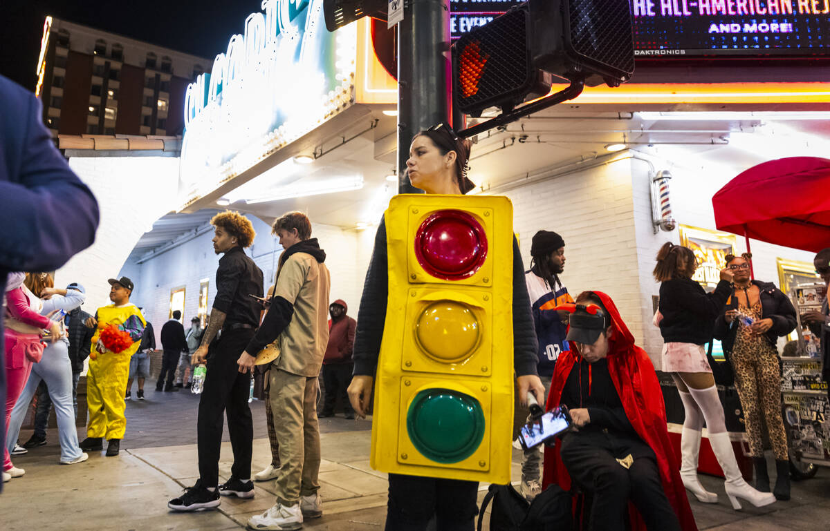 A woman in a traffic light costumes rests against a traffic light pole outside of the El Cortez ...