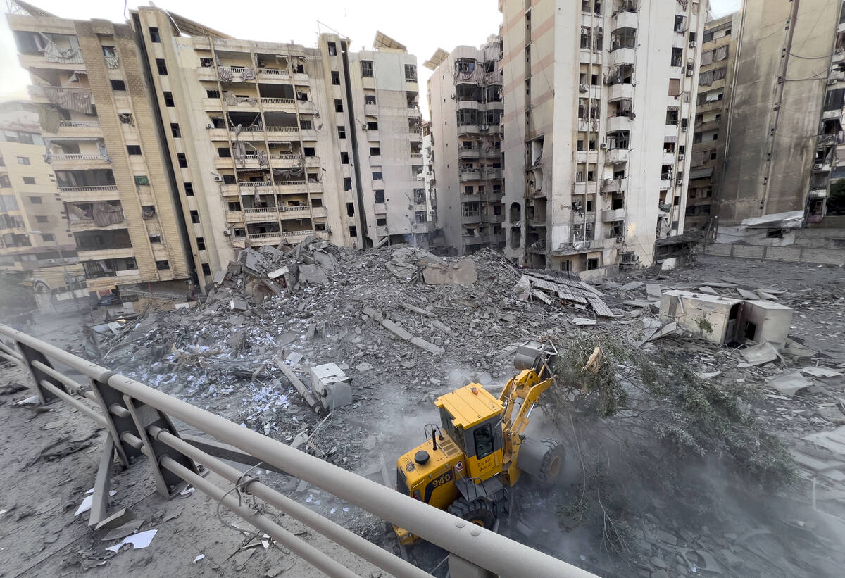 A municipality worker uses a bulldozer to remove the rubble of a destroyed building that was hi ...