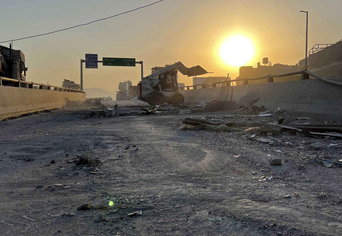 A municipality worker uses a skid steer loader to reopen a bridge closed by the rubble of a des ...