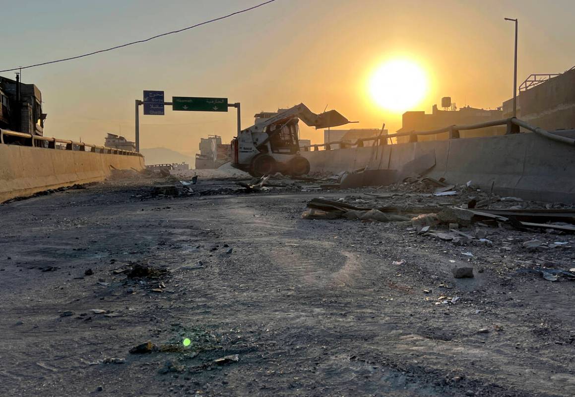 A municipality worker uses a skid steer loader to reopen a bridge closed by the rubble of a des ...