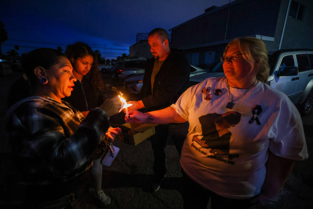 Lori Judd, right, helps light candles for mourners during a vigil for 17-year-old Jonathan Lewi ...