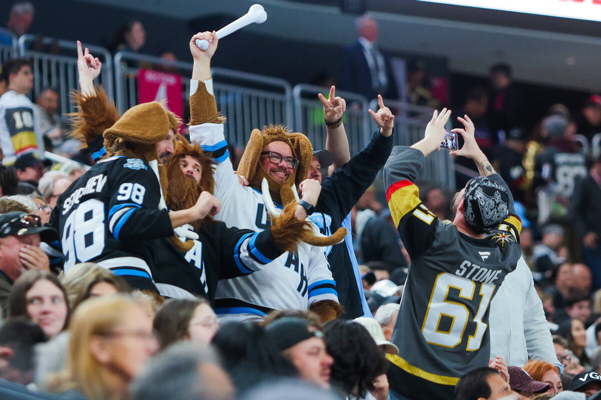 A Golden Knights fan takes a photograph as Utah Hockey Club fans cheer after a goal by the Utah ...