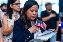 Rosalyn Tuggle stands with others for the Pledge of Allegiance during a naturalization ceremony ...