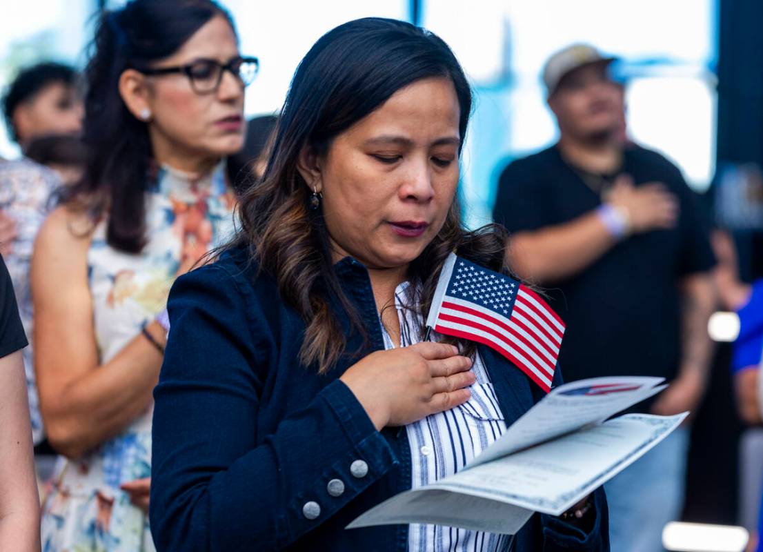 Rosalyn Tuggle stands with others for the Pledge of Allegiance during a naturalization ceremony ...