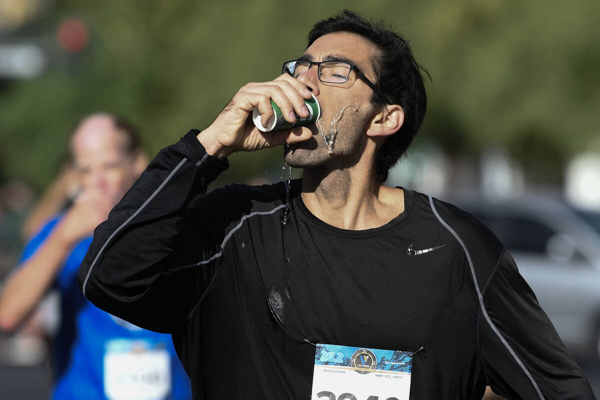 A marathon participant downs a cup of water during the Las Vegas Marathon Sunday, Nov. 3, 2024, ...