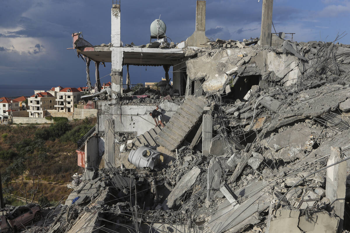 A man inspects a destroyed building hit in an Israeli airstrike, in Ghaziyeh town, south Lebano ...