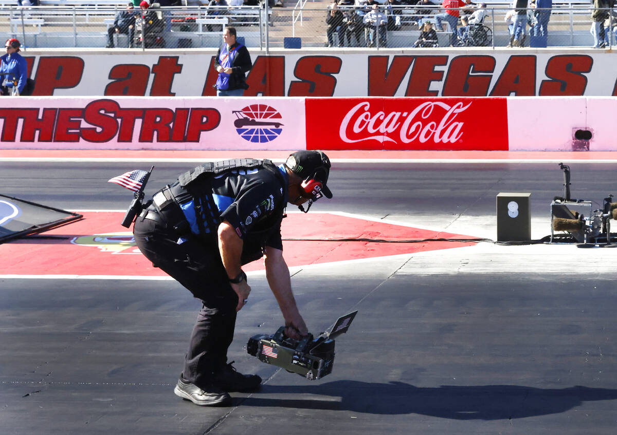 A grown crew takes the temperature off the track surface before the final race of the NHRA Nati ...