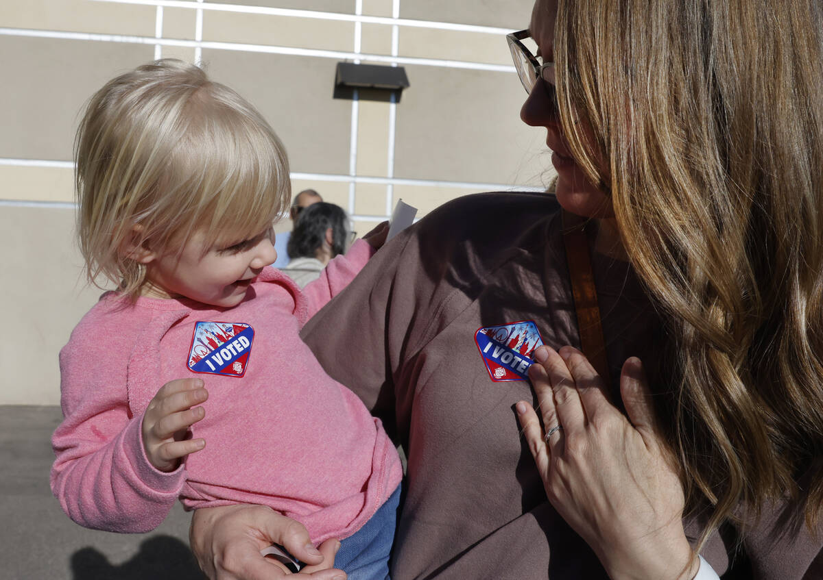 Lindsey Tiberti places her "I Voted" sticker on her chest as her two-year-old Maggie ...