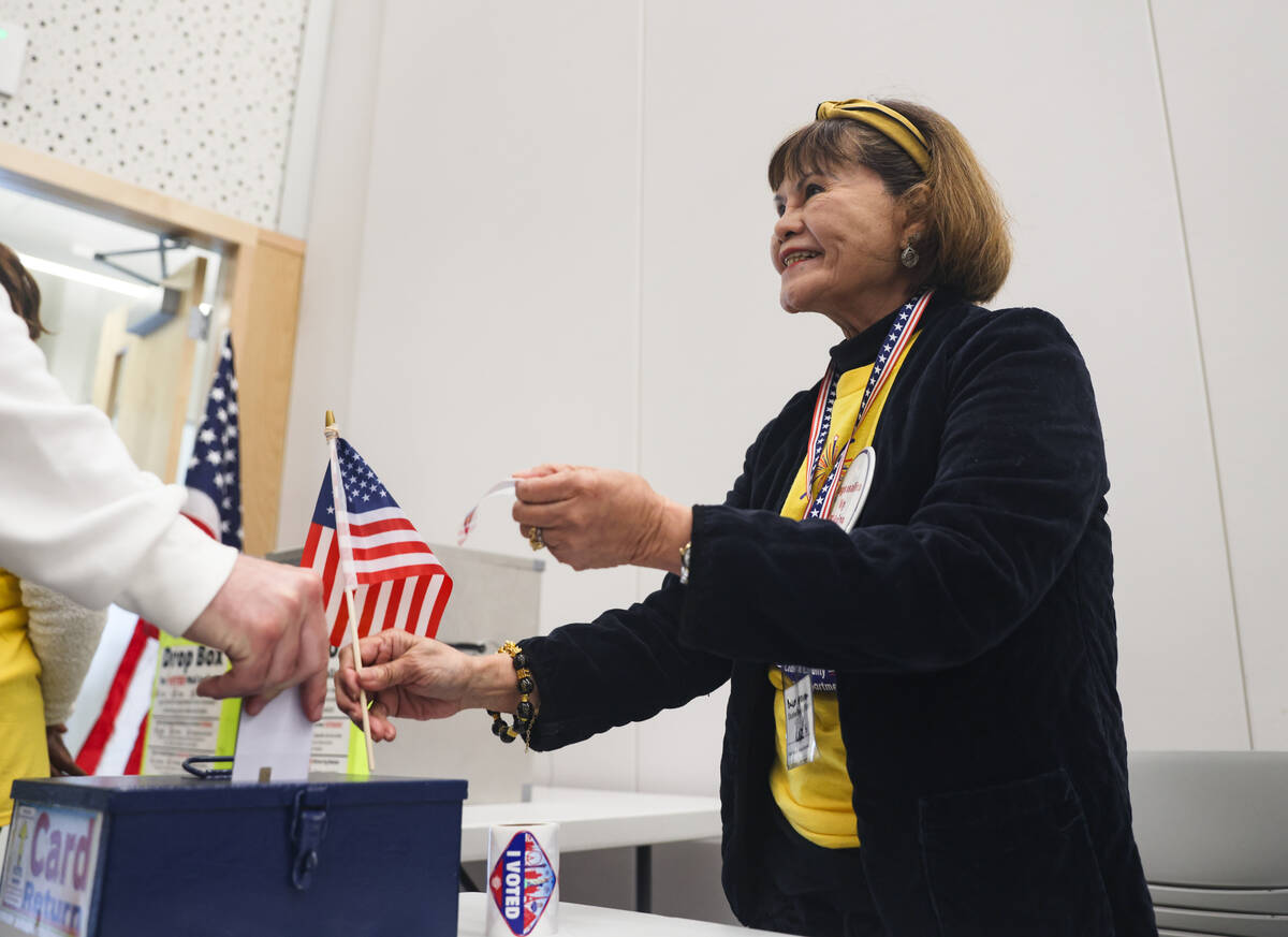 Volunteer Luz Salter hands out stickers to voters at a vote center at the East Las Vegas Librar ...