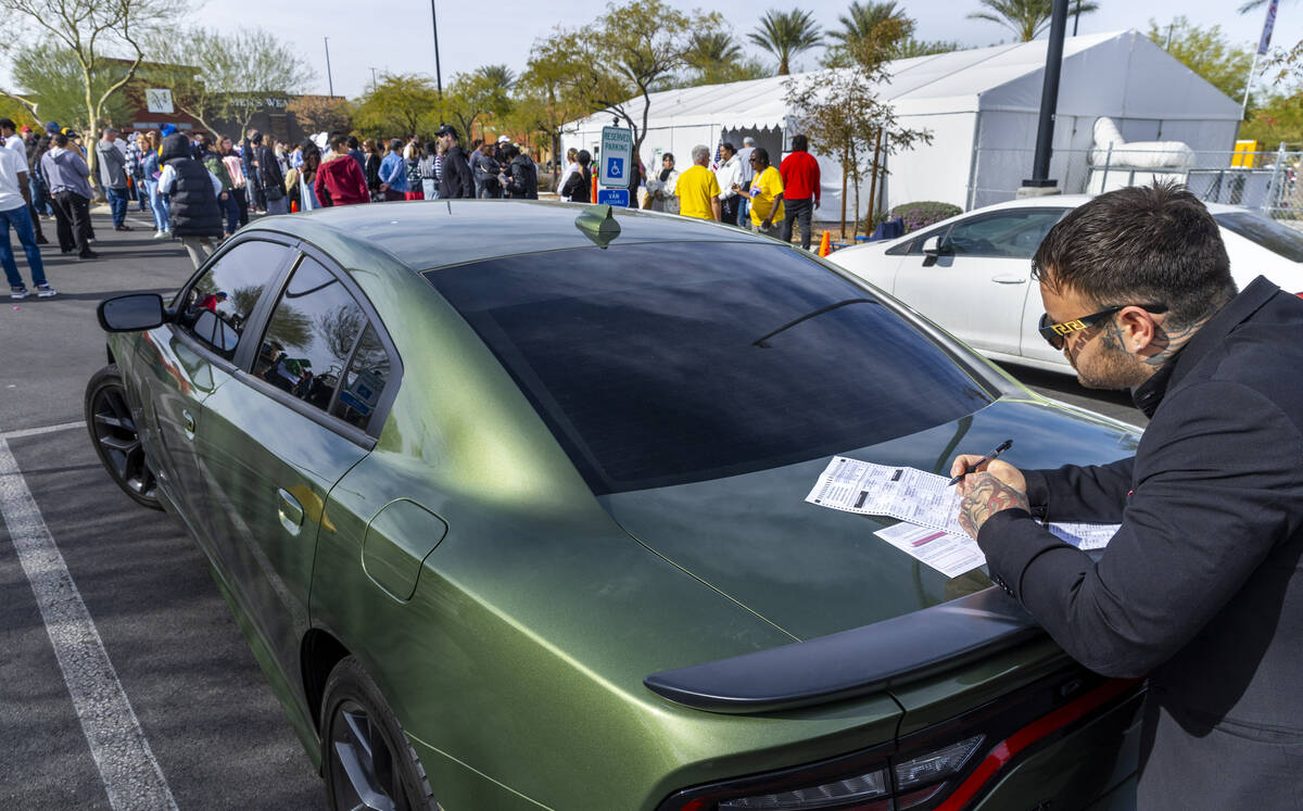 A voter fills out his ballot as people wait in line more than an hour to cast their ballots on ...