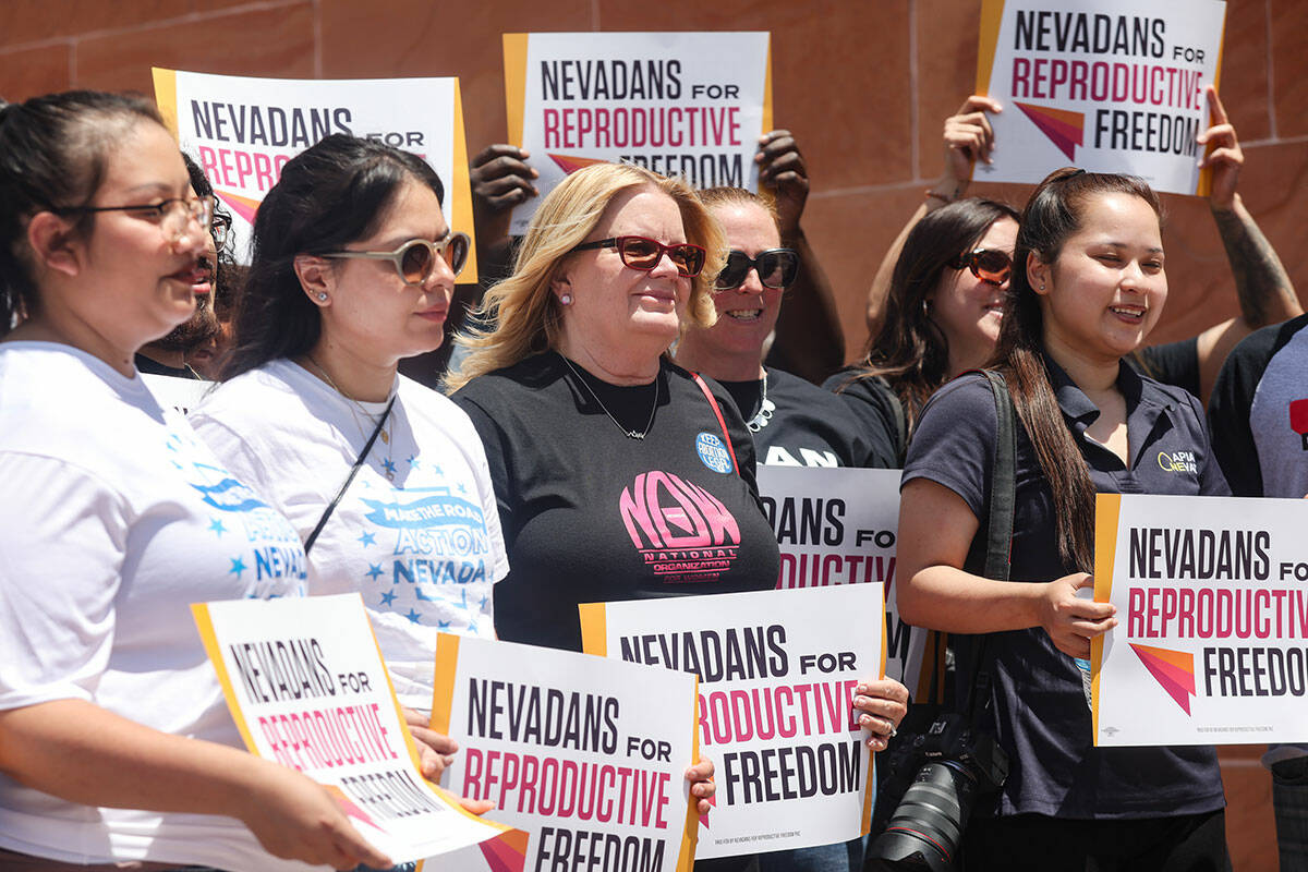 Supporters hold signs at a press conference regarding the over 200,000 signatures submitted to ...