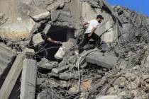 People search for victims at a destroyed building hit in an Israeli airstrike, in Ghaziyeh town ...