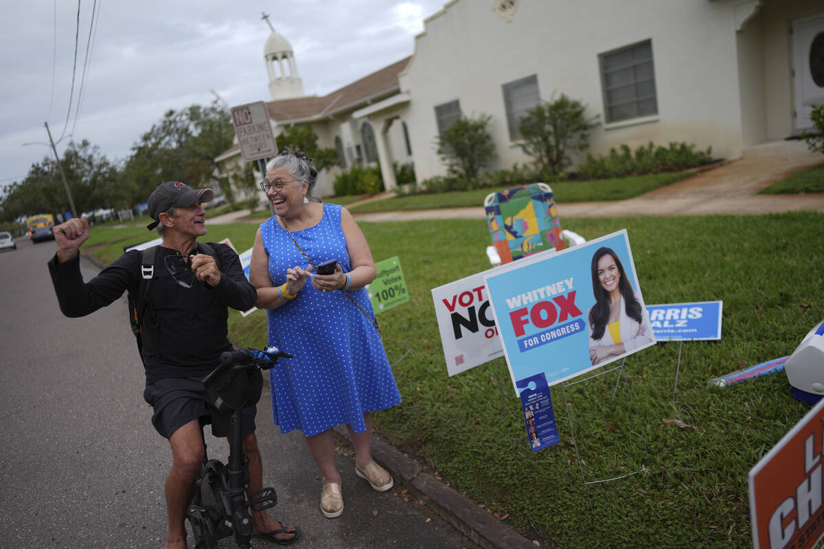 Trump supporter Barney Morin, left, cheers as Democratic poll greeter Lynn Akin helps him find ...