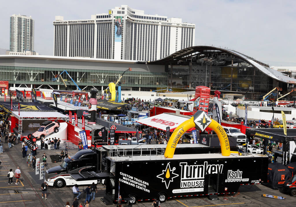 Attendees walk about and view some of the many vehicles on display during the first day of SEMA ...