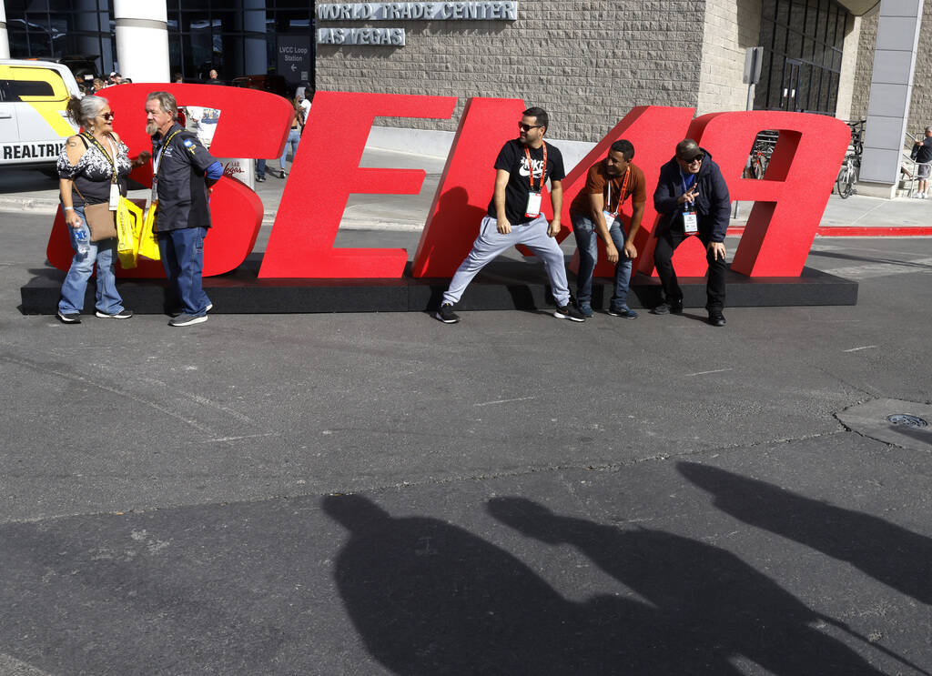 Attendees pose for a photo at a SEMA sign during the first day of SEMA at the Las Vegas Convent ...