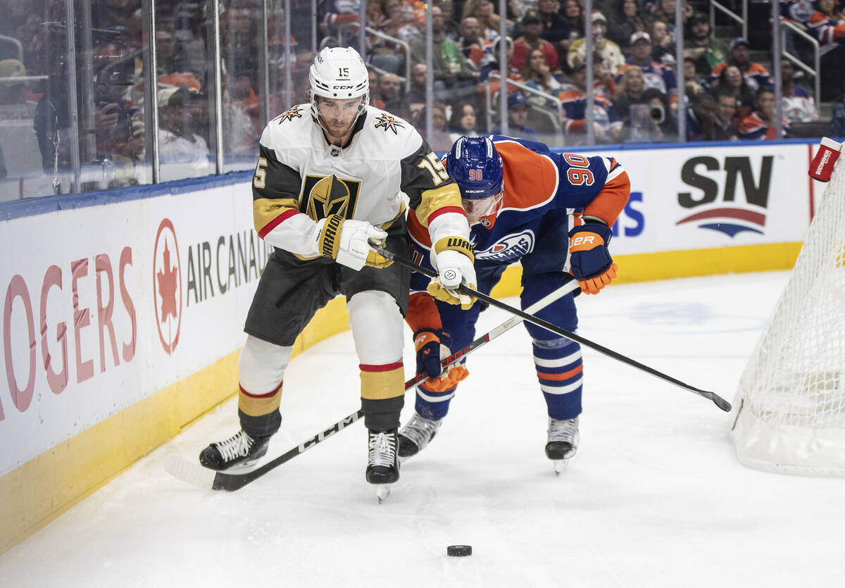 Vegas Golden Knights' Noah Hanifin (15) and Edmonton Oilers' Corey Perry (90) battle for the pu ...