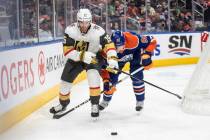 Vegas Golden Knights' Noah Hanifin (15) and Edmonton Oilers' Corey Perry (90) battle for the pu ...