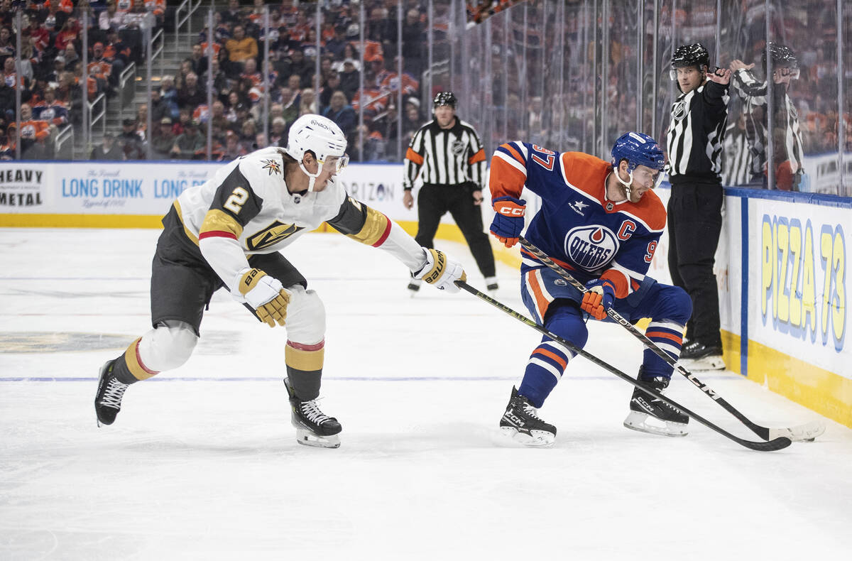 Vegas Golden Knights' Zach Whitecloud (2) tries to get the puck from Edmonton Oilers' Connor Mc ...